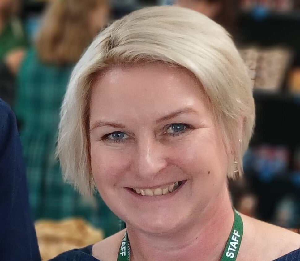 Portrait of director Zoe who has a blonde bob and is wearing a blue top